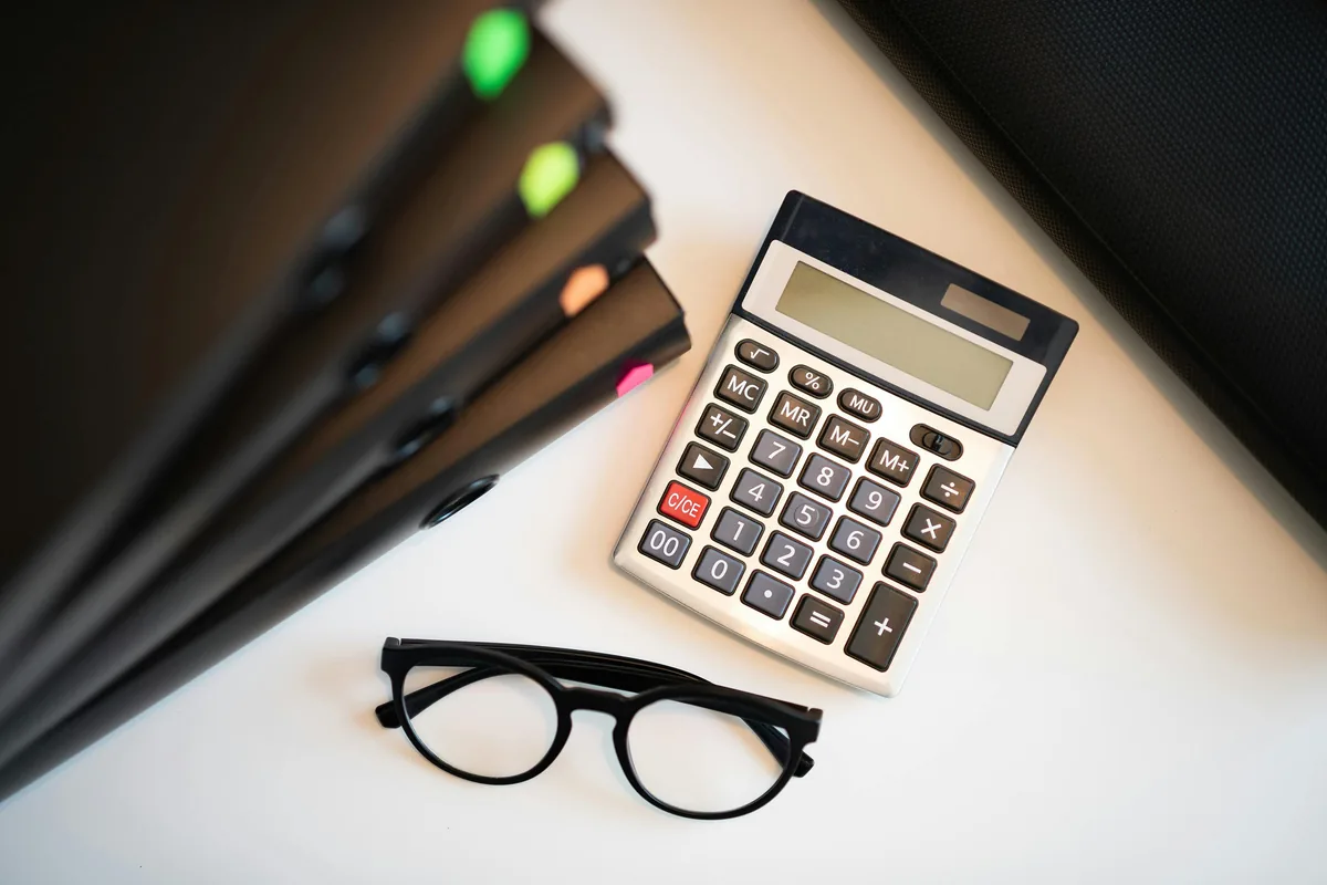 Calculator and reading glasses representing careful review of FineDay Funds APR and loan costs