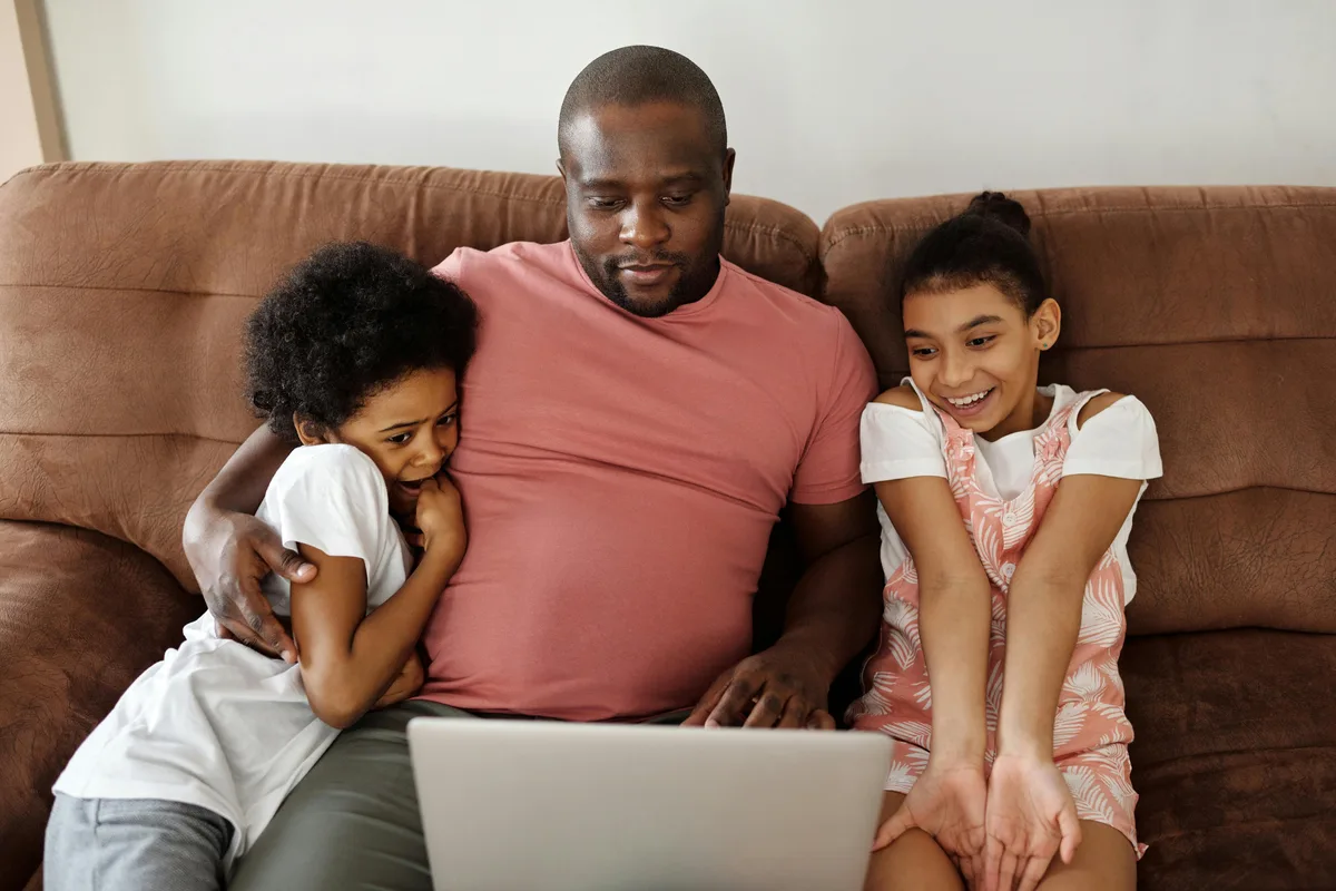 Father with two children browsing the lender loan options on laptop — we serve families of all backgrounds