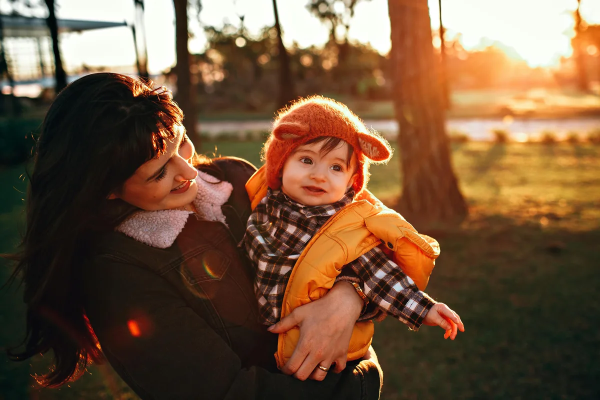 Single mother and child smiling in warm sunlight — the lender helps everyday families through emergencies