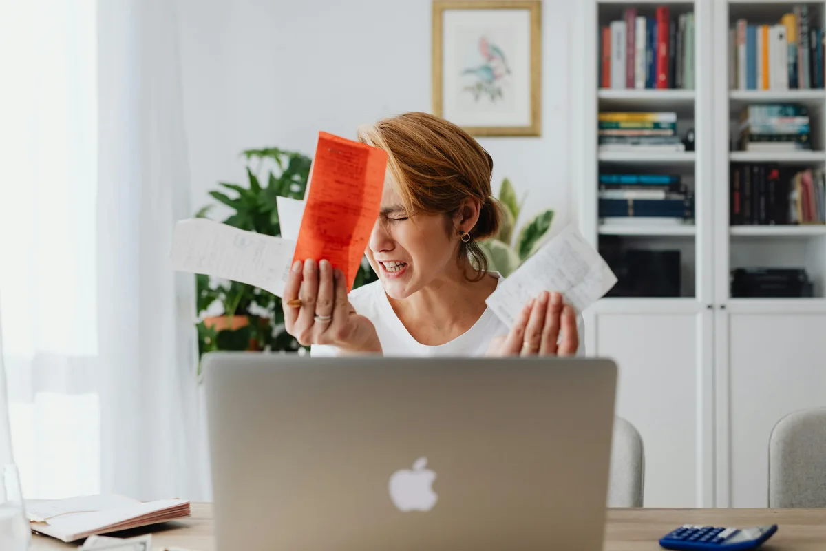 Woman overwhelmed by bills at her desk — the financial stress that leads many to search for emergency loans